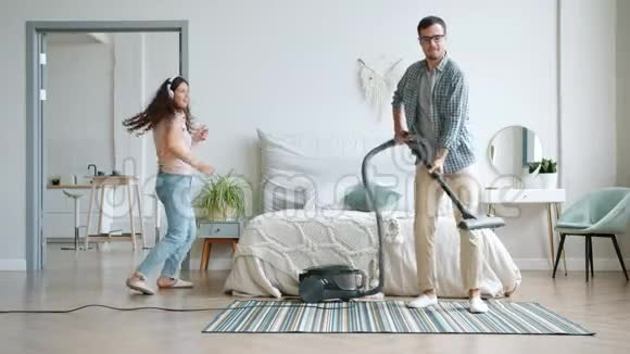 男人和女人跳舞享受用吸尘器打扫音乐的房子视频的预览图