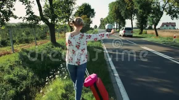 匿名的年轻女士在乡间路上搭便车视频的预览图