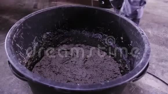 工人把水泥搅拌在容器里库存录像男子在工地上搅拌水泥视频的预览图