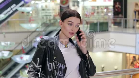 一个穿着皮夹克的女孩在购物中心接电话视频的预览图
