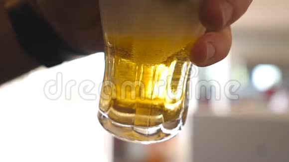 将男酒精手举着玻璃杯倒着淡啤酒冷饮杯子里的小泡泡视频的预览图