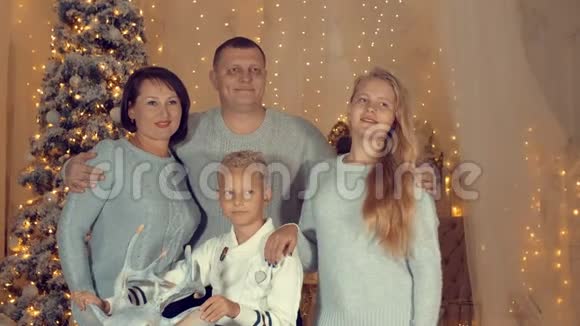 在舒适的客厅里微笑的家人站在圣诞树的背景下视频的预览图