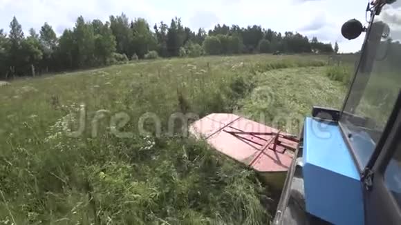 拖拉机与旋转割草机缓慢地骑在一个倾斜的领域在转弯结束视频的预览图
