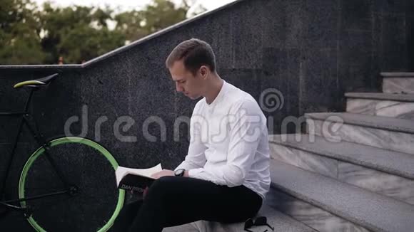 年轻认真的白种人读书坐在城市的楼梯上学习或阅读在城市公园闲暇时间视频的预览图