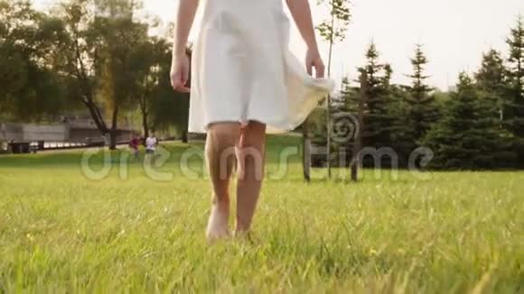 美丽的小女孩光着脚在阳光明媚的的草地上视频的预览图