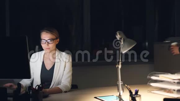 可爱的男同事大胡子男正带着咖啡给深夜在电脑上工作的疲惫的年轻女子视频的预览图