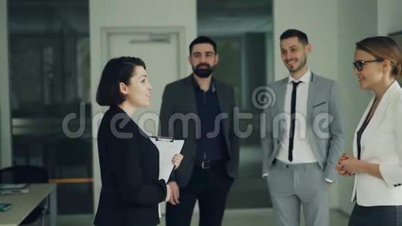 年轻漂亮的女士在成功的公司找到工作和CEO握手微笑着而其他员工视频的预览图