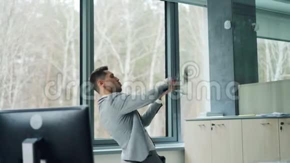 幸福的富商把钱扔在空中独自站在现代办公室表达积极的情感视频的预览图