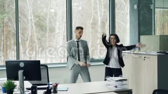 漂亮的女商人正在教她的男同事跳舞听音乐在办公室里享受休息视频的预览图