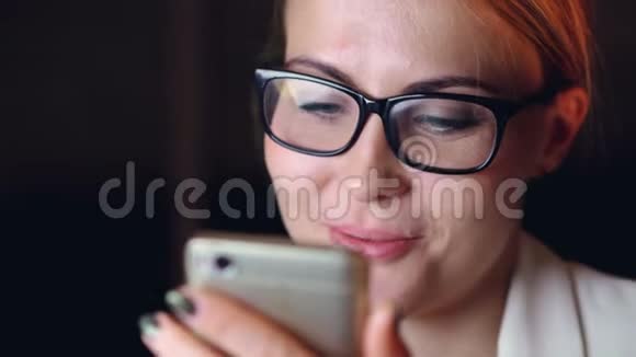 戴着智能手机触摸屏幕上网微笑眼镜的漂亮年轻女士的头像视频的预览图