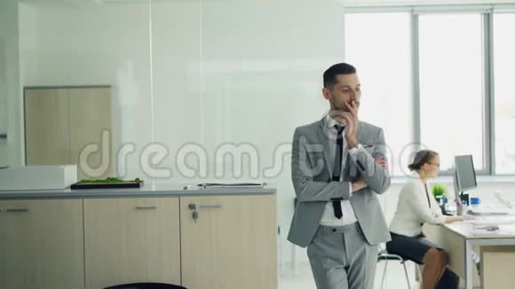 穿着西装的年轻男士站在办公室等待面试而女性面试官则在与她交谈视频的预览图
