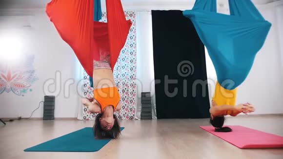 空中瑜伽两个女人倒吊在吊床上视频的预览图