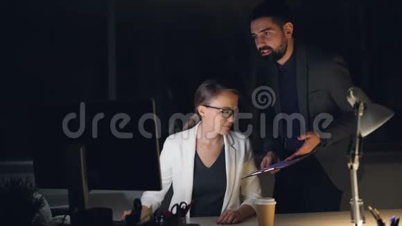 公司首席执行官正在与他的秘书交谈他的秘书在电脑工作的深夜下订单和讨论工作人们是视频的预览图