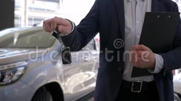 汽车销售中心专业卖车的家伙手里拿着新汽车的钥匙在经销商处销售视频的预览图