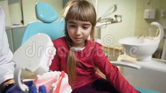非洲牙医教小女孩如何在塑料模型上刷牙视频的预览图