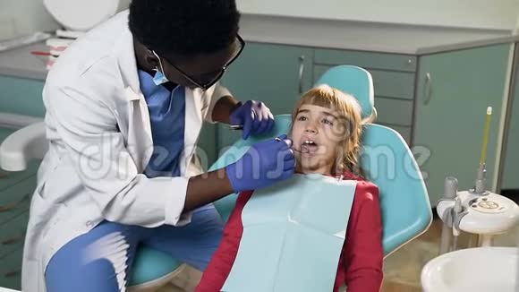非洲男性牙医治疗小女孩的牙齿视频的预览图