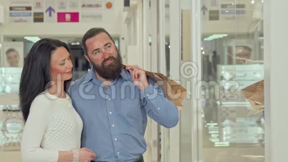 快乐的成熟夫妻在购物中心看服装店的橱窗视频的预览图