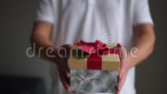 男人的手拿着礼物盒以表示给予圣诞礼物在美丽的包装在男性手中祝你快乐视频的预览图