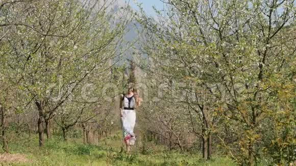 春暖花开的花园里穿着长裙跳跃的年轻美女视频的预览图