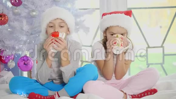哥哥和姐姐在圣诞前夜在一个舒适的客厅里喝热巧克力和玩视频的预览图