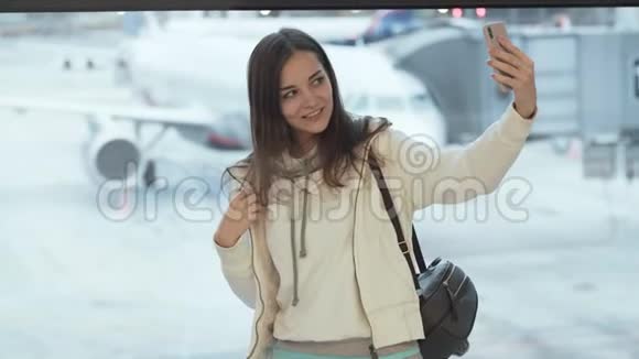 在飞机背景下美女在机场窗口拍摄自拍照片视频的预览图