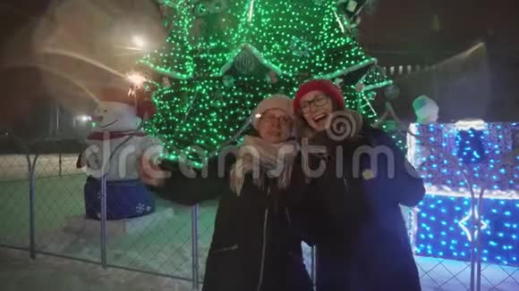 快乐的母亲和带着火花的女儿站在新年树附近玩得很开心视频的预览图