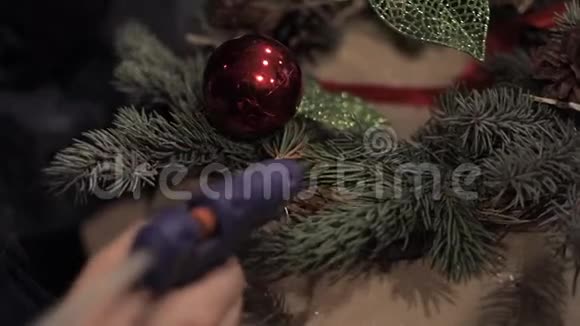 双手合拢将一片人造叶子粘在圣诞花环上视频的预览图