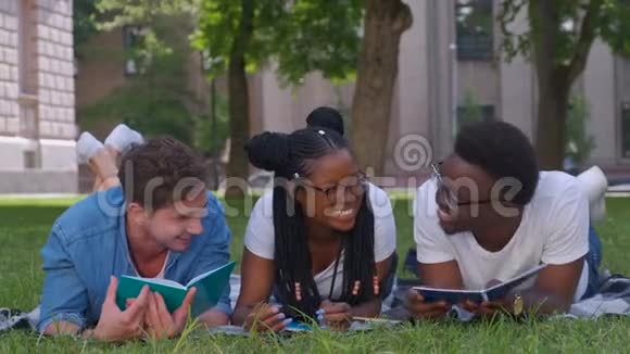 三个学生在户外坐在草地上一起学习读书笔记视频的预览图