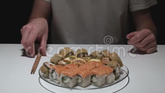一个人在一盘寿司卷前打开棍子视频的预览图