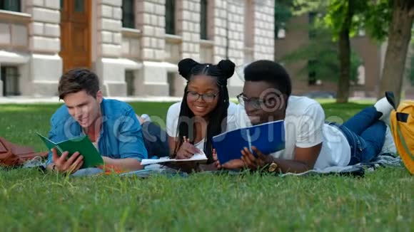 三个学生在户外坐在草地上一起学习读书笔记视频的预览图