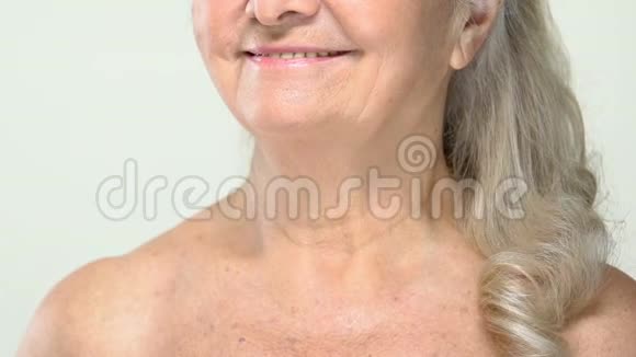 白发苍苍的老年妇女用化妆刷美容面罩涂粉视频的预览图