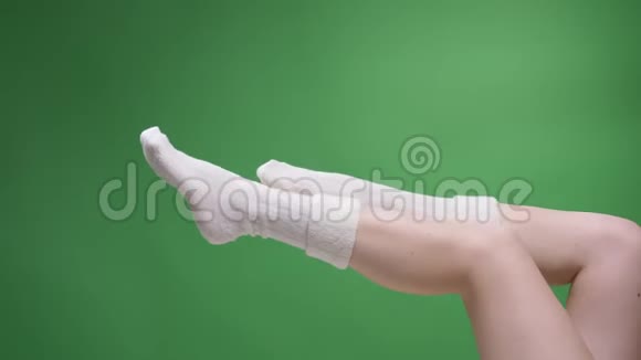 特写侧景拍摄女腿在可爱的短白袜子诱人的移动与背面孤立的绿色视频的预览图