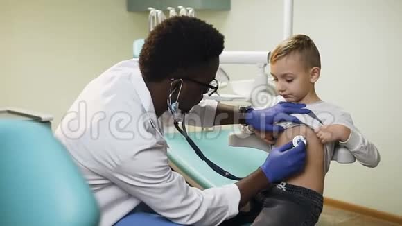 英俊的非洲医生在医院办公室检查小男孩视频的预览图