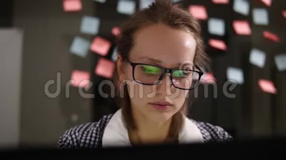 有笔记本电脑的女人戴眼镜的年轻女人在办公室的笔记本电脑上工作商业女性办公室工作人员女孩视频的预览图