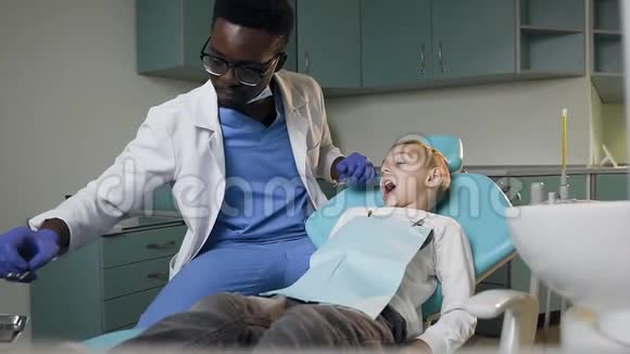 年轻的牙医检查小男孩的牙齿视频的预览图