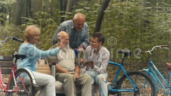 老年人看着公园里的平板电脑屏幕视频的预览图