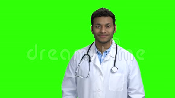 英俊的医生看着绿色屏幕上的相机视频的预览图