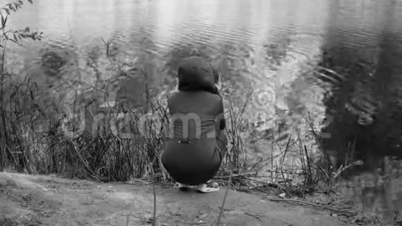 冻僵的女孩从寒冷中颤抖坐在河岸上悲伤戏剧单色视频视频的预览图