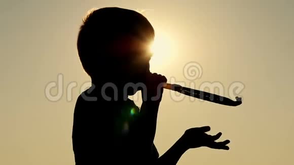 一个快乐的孩子的剪影吹着节日的舌头口哨那个男孩吹口哨视频的预览图