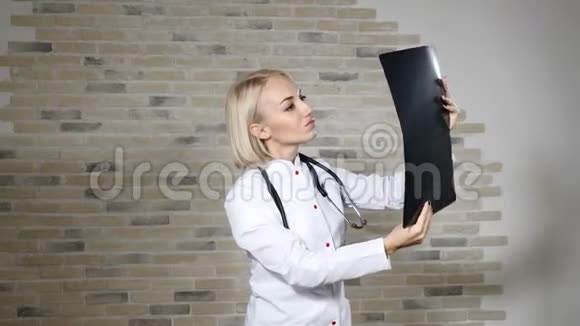 一位漂亮的金发女医生穿着白色的医用礼服在医疗诊所检查x光健康观念4k视频的预览图