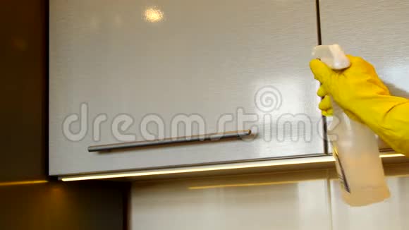 女人一只黄色的橡胶手套用洗涤剂和布清洁现代塑料厨房橱柜的表面自负视频的预览图