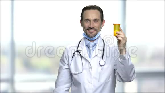 有吸引力的成熟医生带着药丸展示瓶子视频的预览图