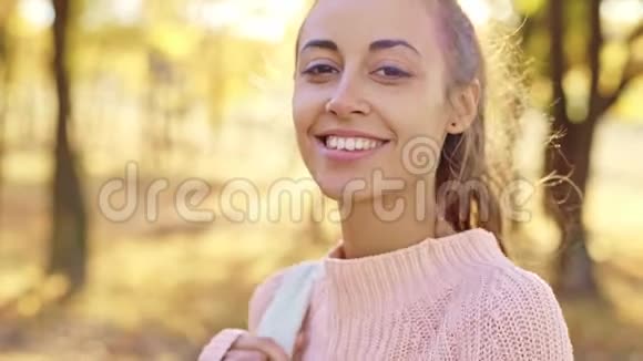 阳光明媚的秋日年轻的女徒步旅行者漫步在明亮的秋天森林里视频的预览图