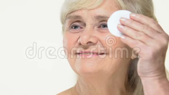 幸福的老年妇女用化妆棉涂抹护面霜视频的预览图