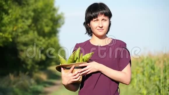 一个年轻的女农民走过田野戴着草帽扛着玉米作物耕作收获和视频的预览图