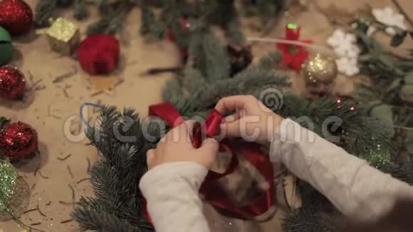 女性的双手收紧圣诞花环上的红色丝带视频的预览图