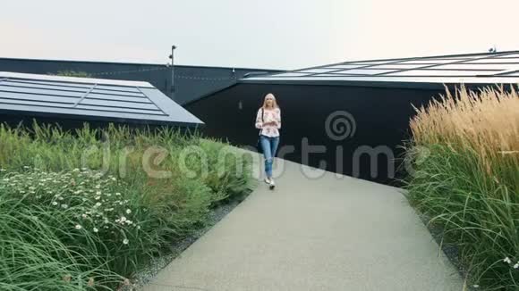 有智能手机的女人走在商场的绿色屋顶上视频的预览图