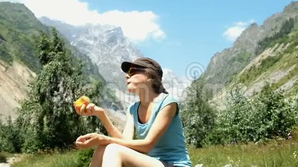 女人坐在石头上吃山背景上的桃子视频的预览图
