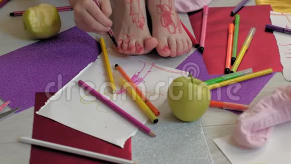 小女孩用毛毡尖笔在脚上画画孩子们创造力发展视频的预览图