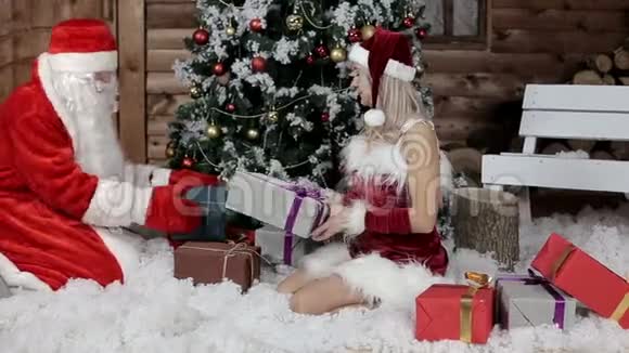 圣诞老人和他的孙女在圣诞树下布置礼物视频的预览图